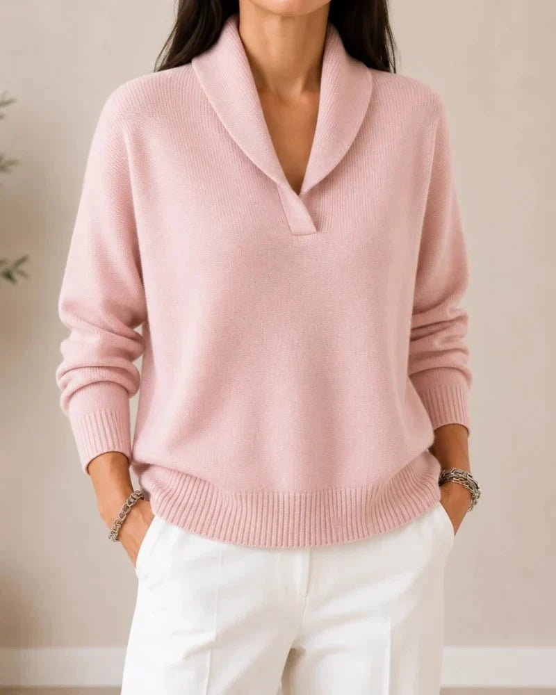 Front view of the jumper in soft pink on a model wearing white trousers, showing the shawl collar and ribbed hem. 12