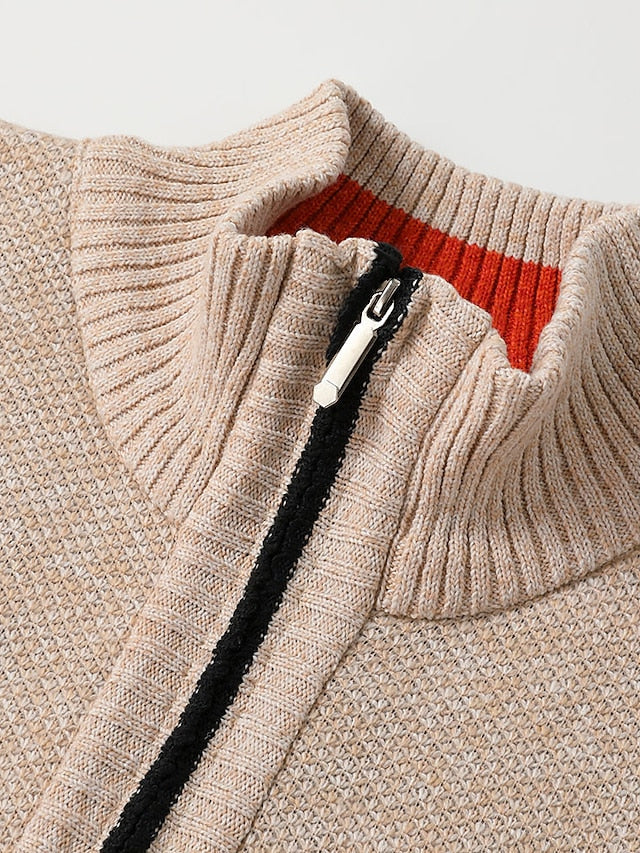 Close-up of the beige cardigan's ribbed stand collar and metal zip puller, with a black zip tape and orange inner collar stripe. 9