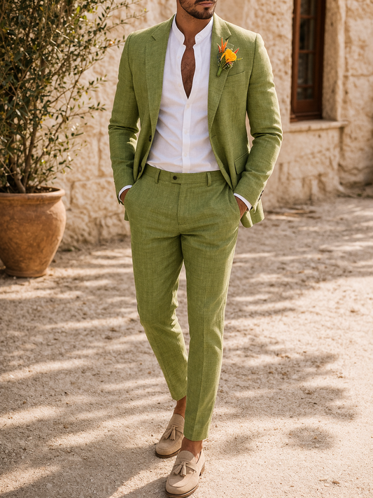 Model in the olive-green suit with hands in pockets, worn over a white collarless shirt with an orange boutonniere and tasselled loafers. 1