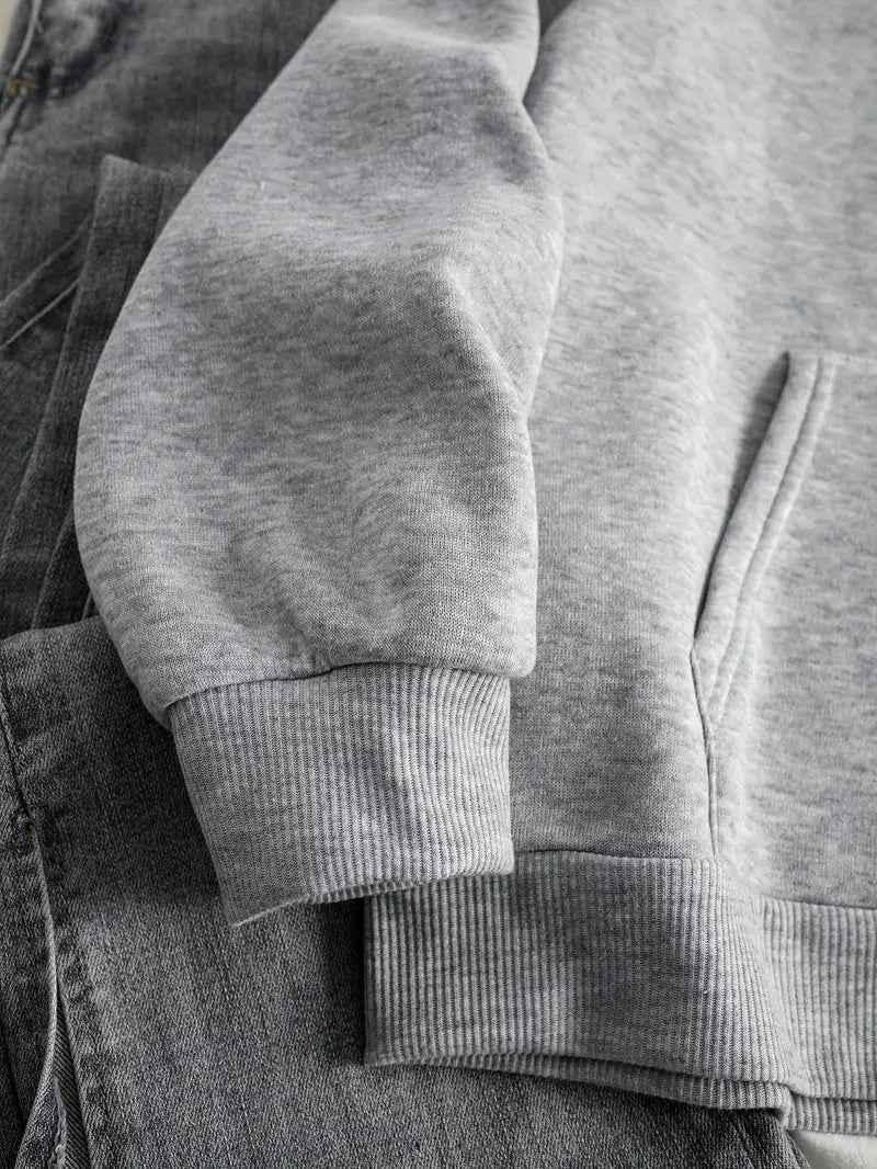 Close-up detail of the grey hoodie's ribbed cuff and hem and the front pocket, resting on grey denim. 5