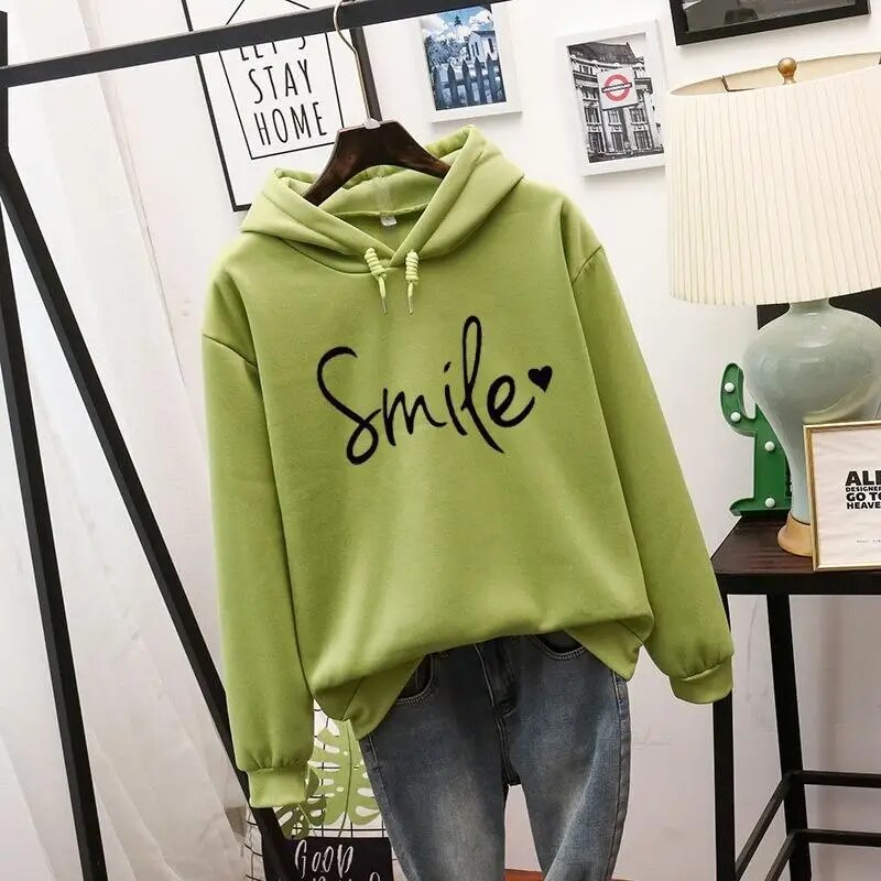 Light green hooded sweatshirt with black script slogan and small heart, drawstring hood and ribbed cuffs, hung over blue jeans. 5