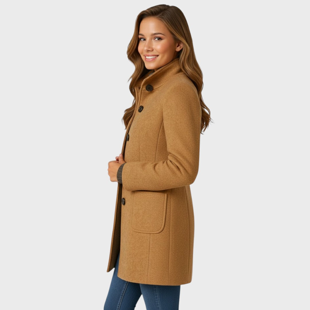 Side view of the camel coat on a smiling model, showing the stand collar, buttons, patch pocket and sleeve. 9