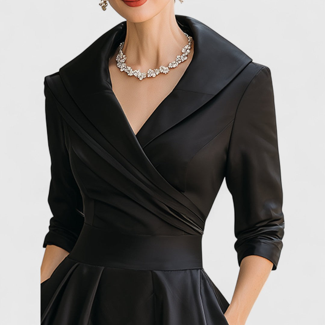 Close-up of the black dress bodice showing the pleated wrap front, wide shawl collar, three-quarter sleeves and waistband. 12