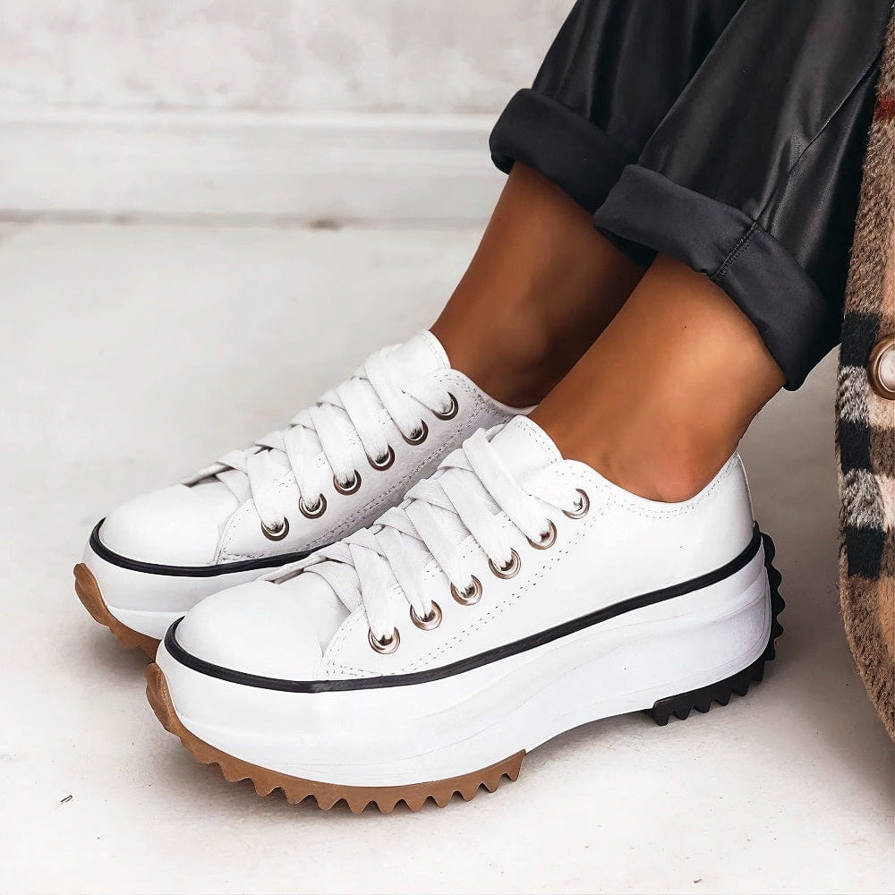 White lace-up platform trainers with a thin black stripe on the chunky sole and gum tread, worn with cuffed black trousers. 4