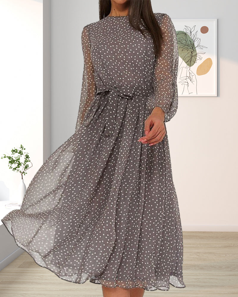 Flowing grey polka dot dress with belted waist, worn in a room with a framed botanical print and potted plant. 4