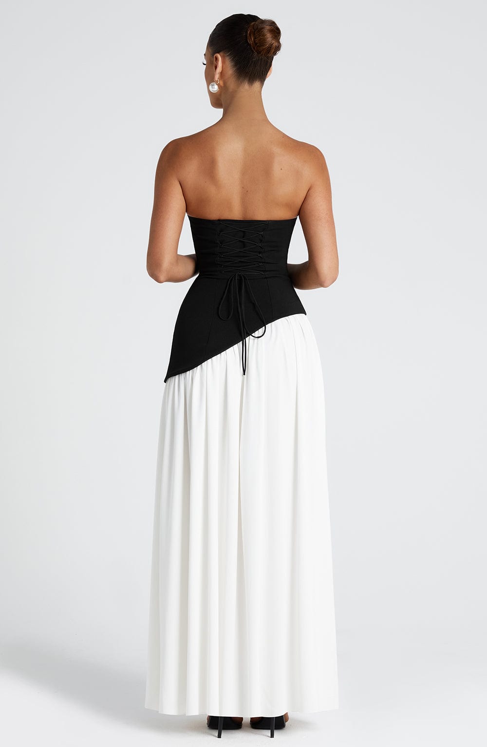 Back view of the black and white dress, showing the black lace-up corset back and long white pleated skirt. 10
