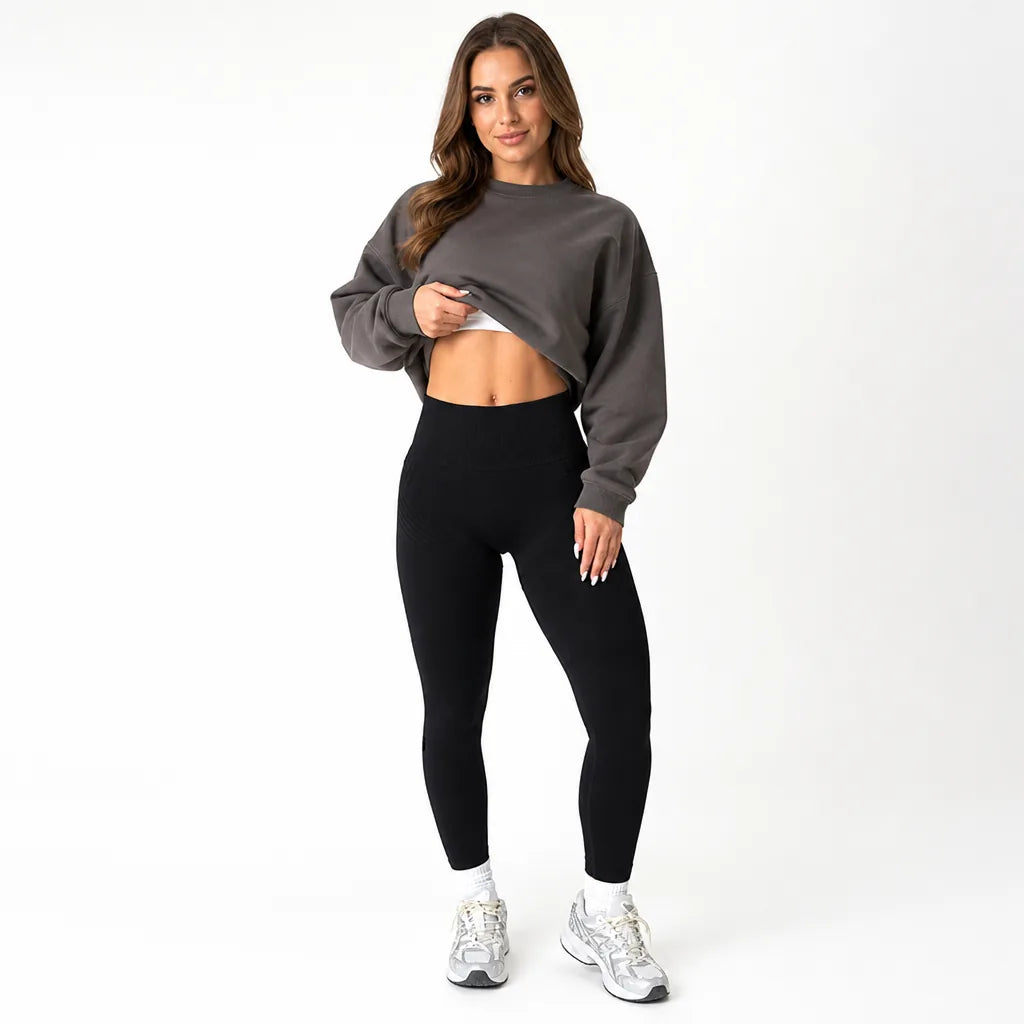 Front view of black high-waisted leggings styled with a grey cropped sweatshirt lifted to show the waistband. 5