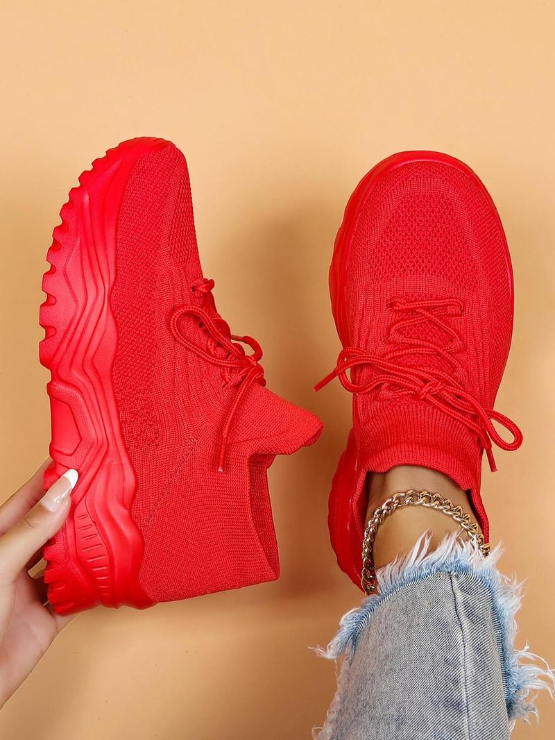 Top-down view of all-red knit sneakers with matching chunky red soles, one held in a hand and one worn. 17