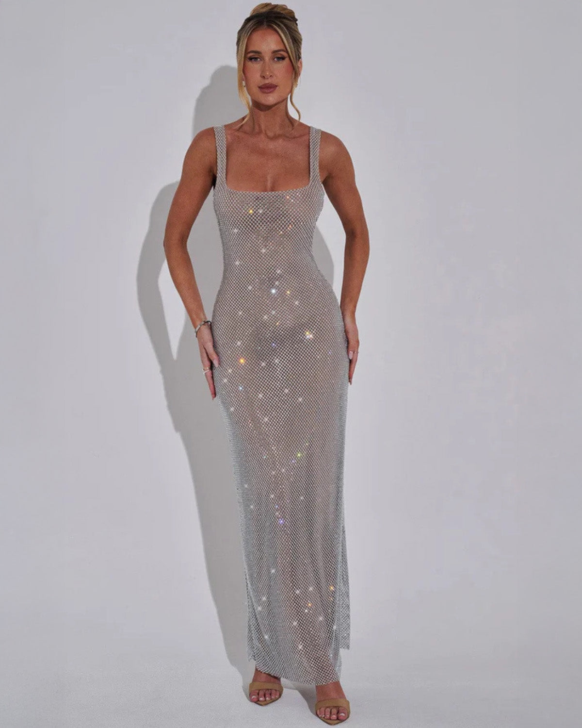 Model facing forward in the silvery grey rhinestone mesh maxi dress with square neckline, arms relaxed at her sides. 6