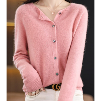 Soft pink cardigan on a model with one hand in her pocket, showing the fuzzy knit, grey buttons and ribbed cuffs. 2