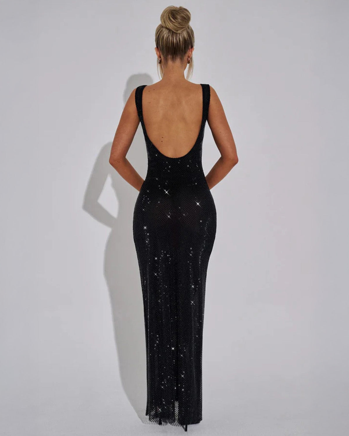 Back view of the black sparkling mesh maxi dress, showing the scooped open back and fitted skirt to the floor. 12