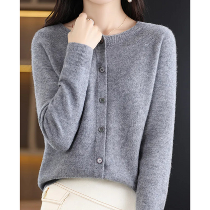 Grey marl cardigan on a model with one hand at her collar, showing the round neck, ribbed cuffs and grey buttons. 7