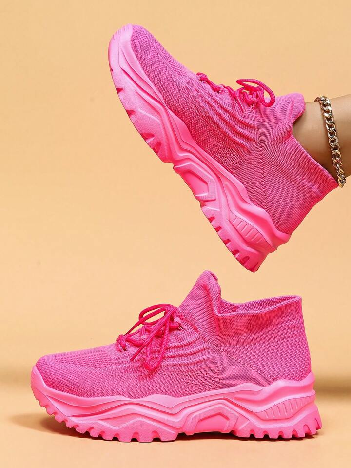 Side view of bright pink knit sneakers with matching chunky pink soles, one shoe raised above the other. 13