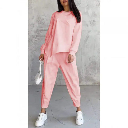 Model wearing the pale coral pink set, front view, carrying a small white bag, shown on a plain white background. 7
