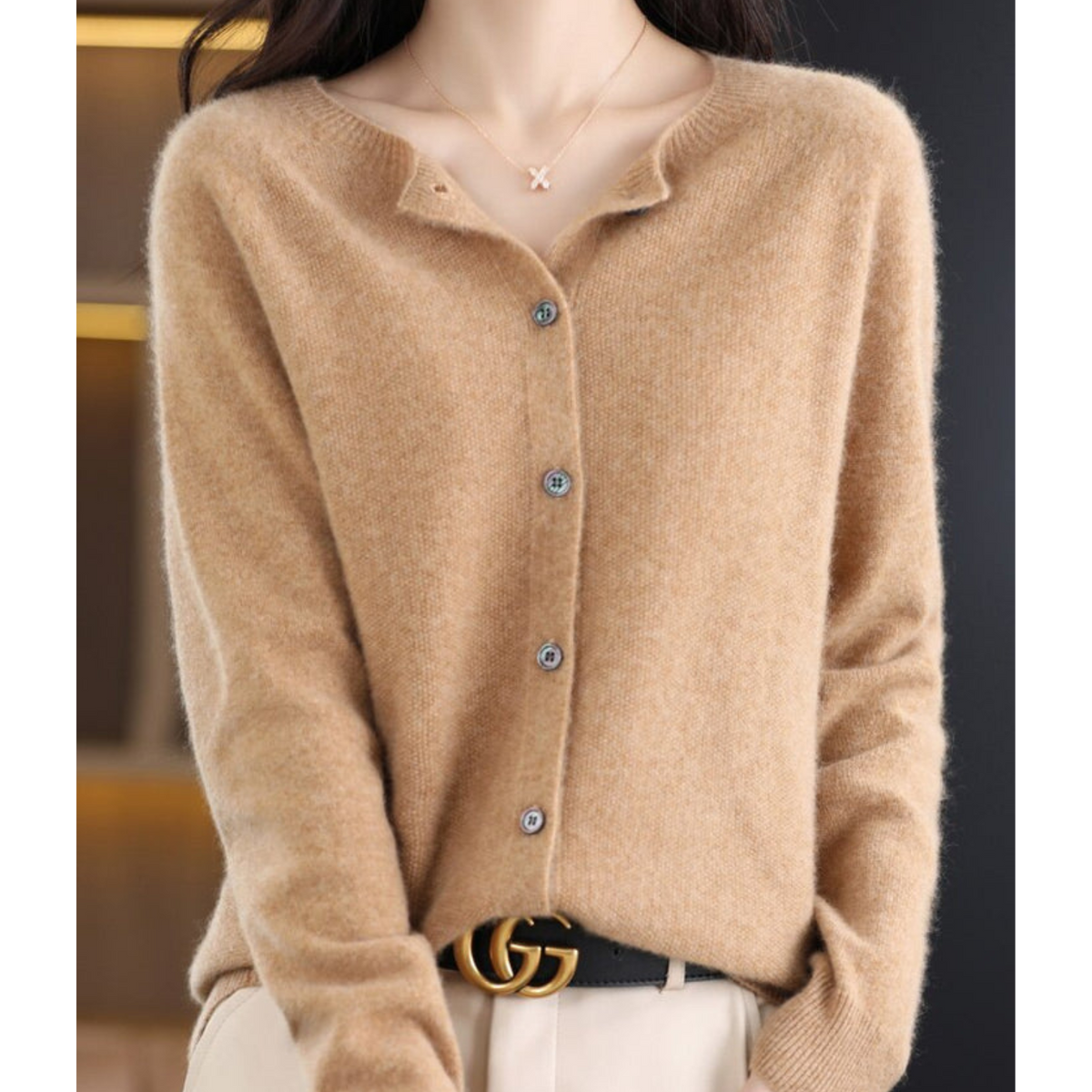 Camel cardigan on a model with a dainty pendant necklace, collar slightly open, buttons fastened and a black belt at the waist. 11