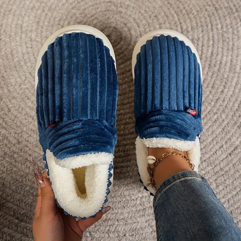 Dark blue ribbed slippers from above, one held to show the fleece lining and one worn on a foot. 15