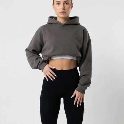 Close crop of black leggings at the waist, worn with a grey cropped hoodie over a white top. 6