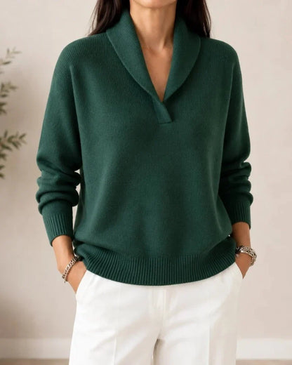Front view of the dark green ribbed-trim jumper on a model with white trousers, hands in pockets, showing the shawl collar. 2