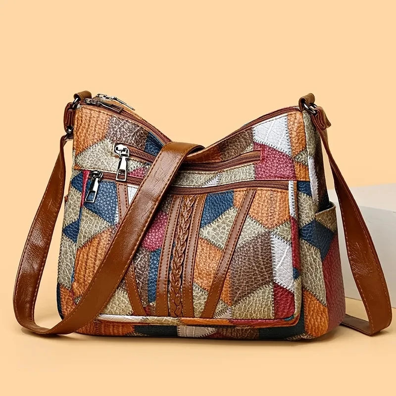 Bag standing upright with the brown strap lying across the front, showing the colourful geometric patchwork panels. 6