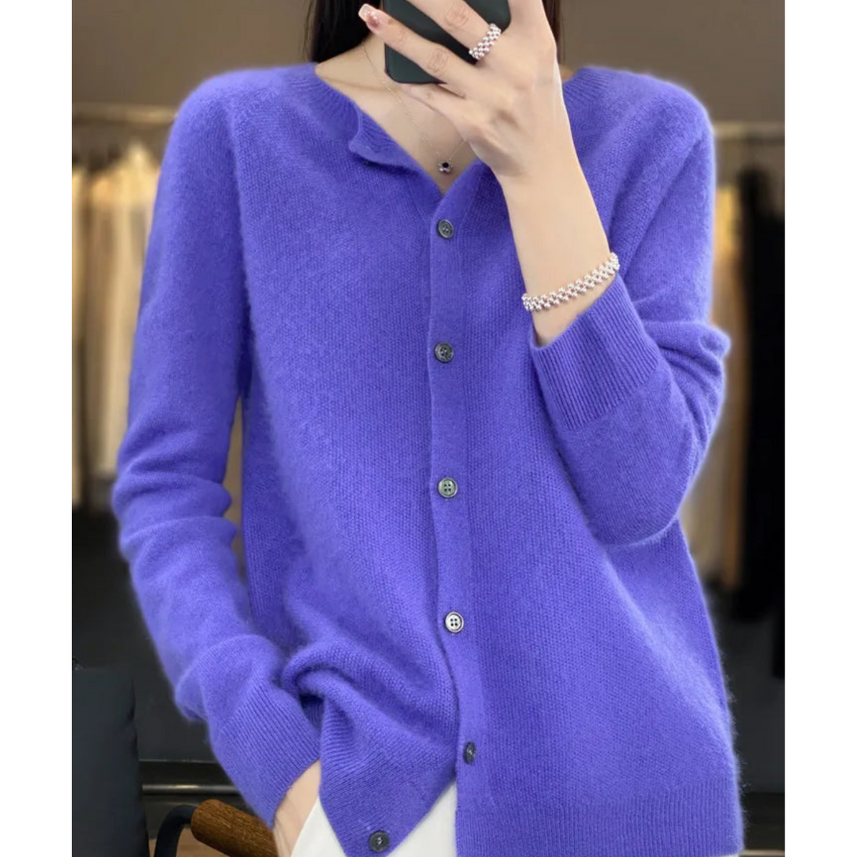 Model in a vivid violet-blue cardigan taking a mirror selfie, worn open at the hem with a pearl bracelet. 3