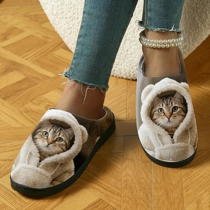 Slippers worn by a model on a parquet floor, showing the printed tabby cat in a fluffy hood on each toe. 3