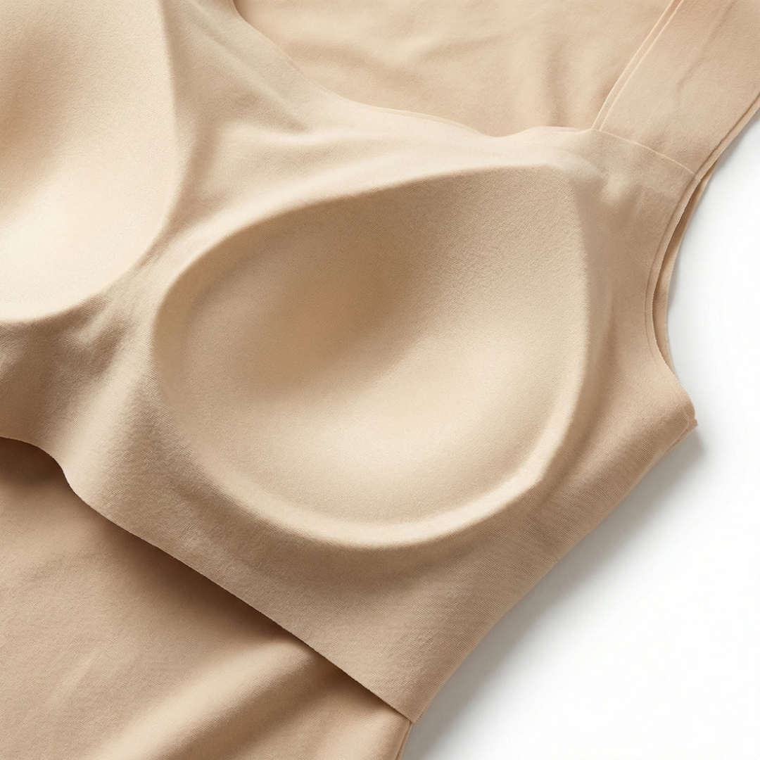 Close-up of the inner moulded bra cup and bonded seamless edges of a beige top, laid flat on white. 8