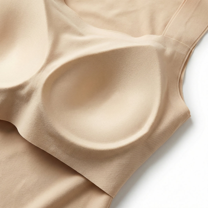 Close-up of the inner moulded bra cup and bonded seamless edges of a beige top, laid flat on white. 8
