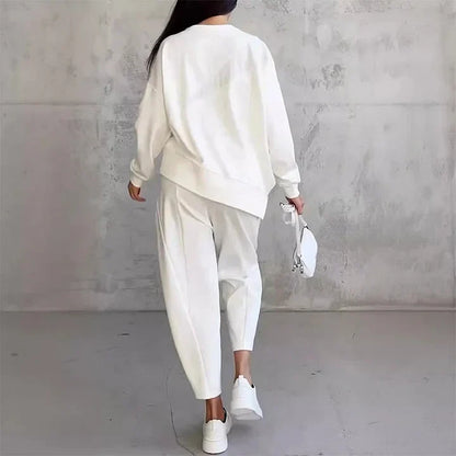 Back view of the white set on a model walking away, showing the loose sweatshirt, tapered trousers and white trainers. 9