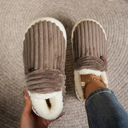Brown ribbed slippers seen from above, one held up to show the white fleece interior and one worn. 14