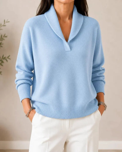 Front view of the jumper in pale sky blue on a model wearing white trousers, hands in pockets. 11