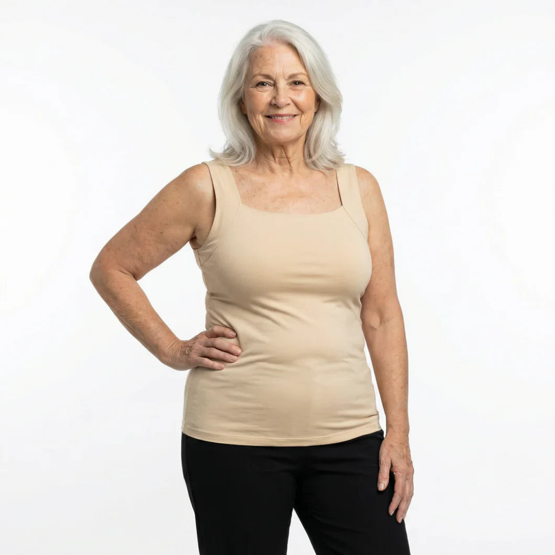 Smiling grey-haired woman wearing the beige square-neck sleeveless top with wide straps and black trousers, one hand on her hip. 5