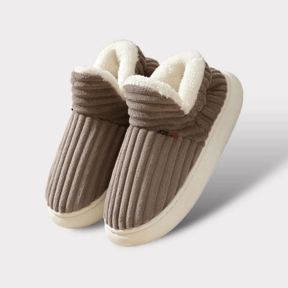 Pair of brown ribbed fleece-lined slippers with thick cream soles, shown on a plain light background. 19
