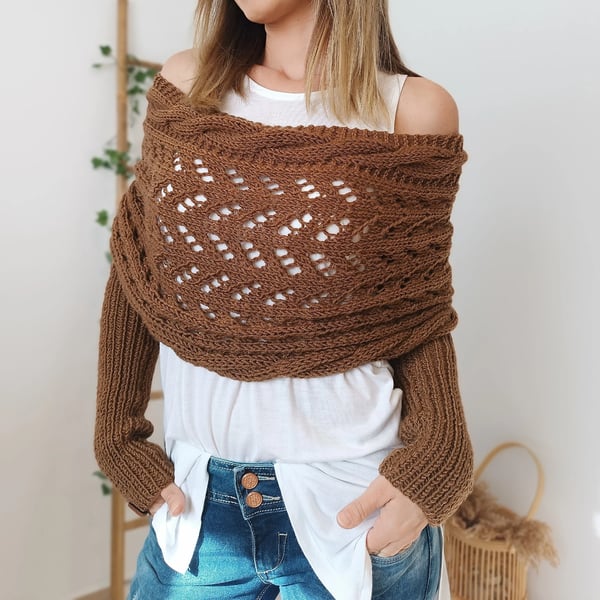 Rust-brown wrap worn off both shoulders, showing the lace panel and chunky ribbed sleeves over a white top. 18