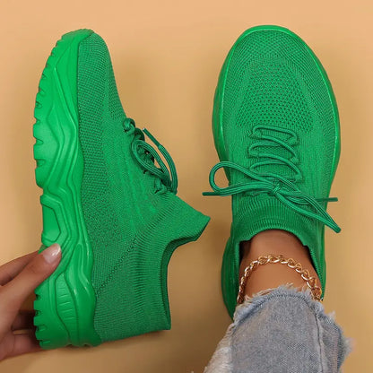 Top-down view of vivid green knit sneakers with matching chunky green soles, one held in a hand and one worn. 19