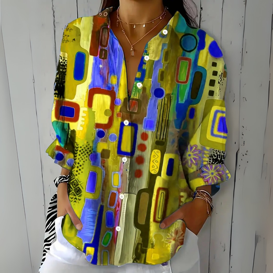 Model wearing the blouse in a yellow and olive colourway with blue and purple abstract shapes, with sleeves rolled to the forearm. 5
