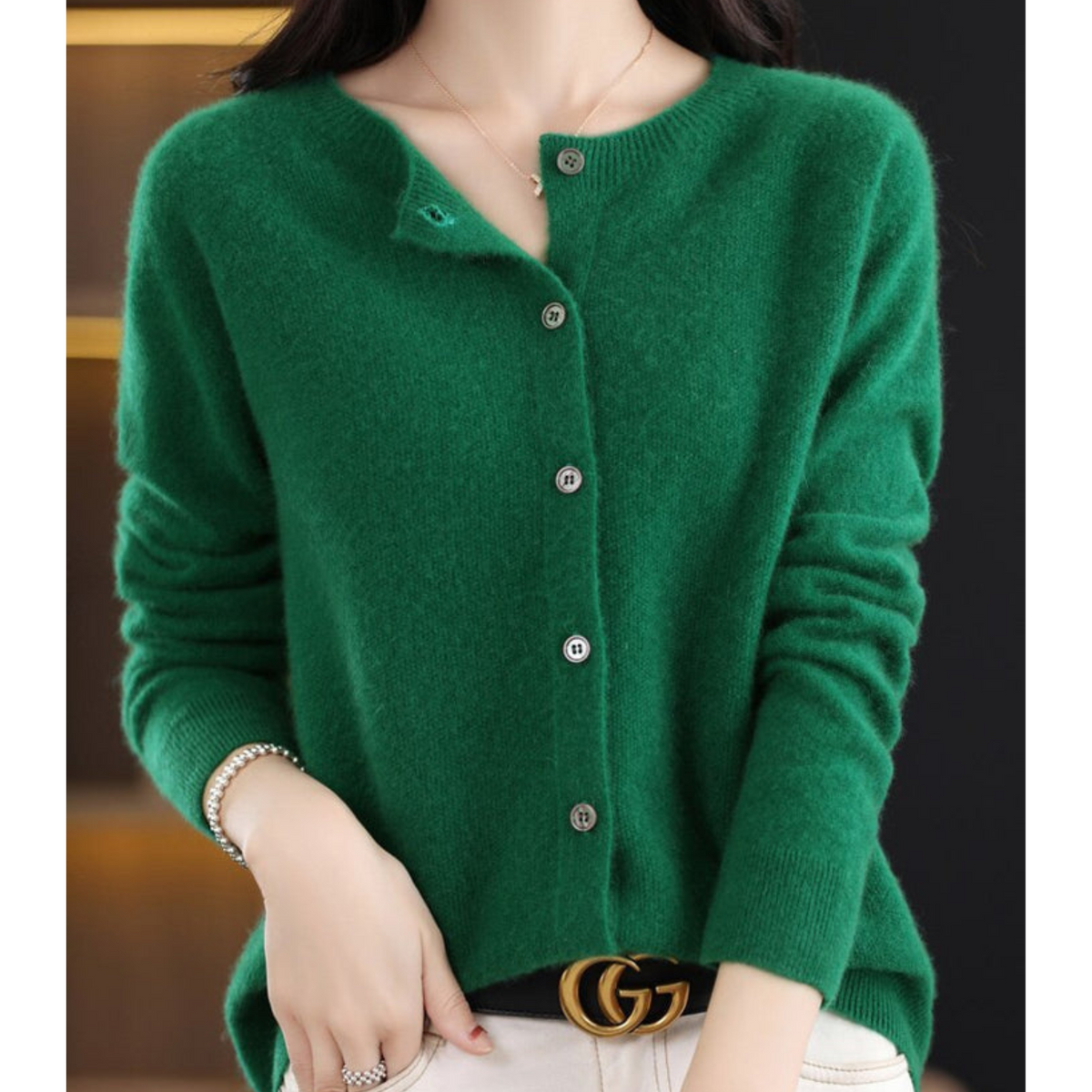 Deep emerald green cardigan on a model, collar open at the top button, hand in her pocket and a pearl bracelet on her wrist. 12