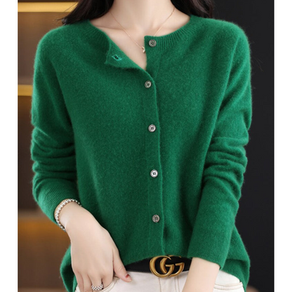 Deep emerald green cardigan on a model, collar open at the top button, hand in her pocket and a pearl bracelet on her wrist. 12