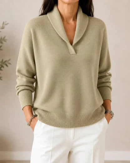 Front view of the jumper in a soft sage green on a model wearing white trousers, with ribbed cuffs and hem. 9