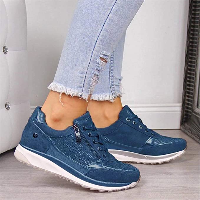 Model wearing the blue version of the zip-sided trainers with ripped jeans, showing the studded panel and white sole. 3