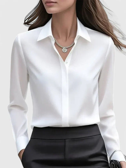Front view of the white satin blouse on a model, with pointed collar and concealed button placket, tucked into black trousers. 2