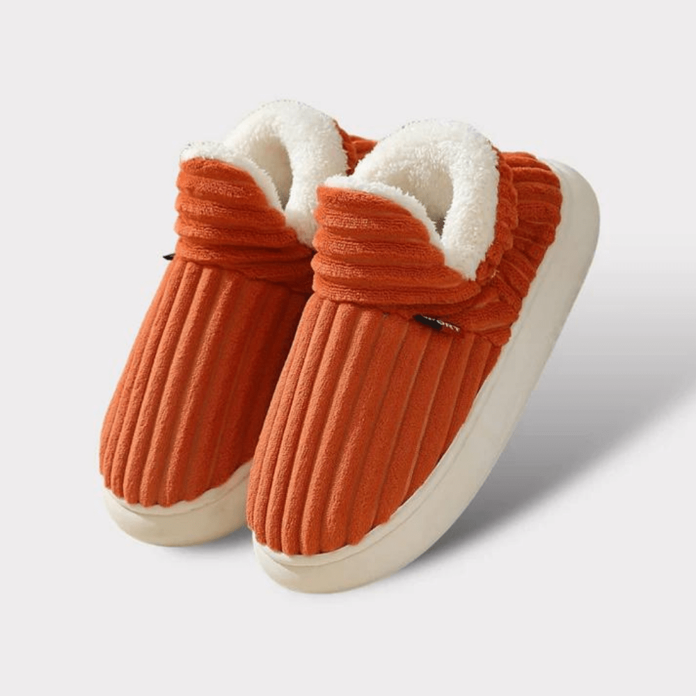 Pair of orange ribbed fleece-lined slippers with thick cream soles, shown on a plain light background. 18