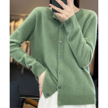 Sage green cardigan worn by a model taking a mirror selfie, buttoned up the front with the bottom button left open. 13