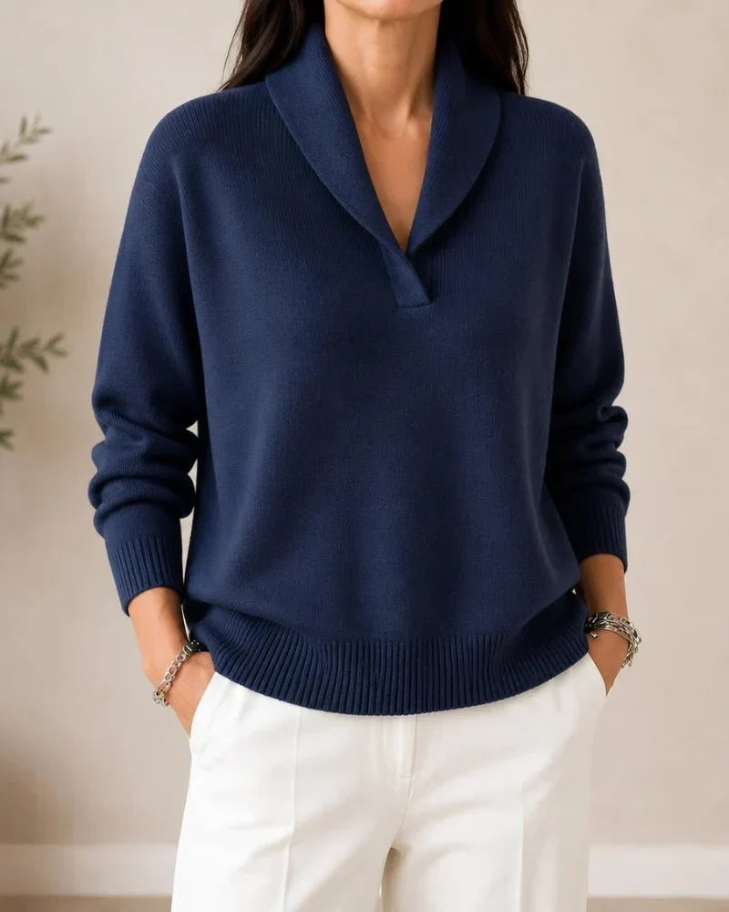 Front view of the jumper in navy blue on a model wearing white trousers, hands in pockets. 7