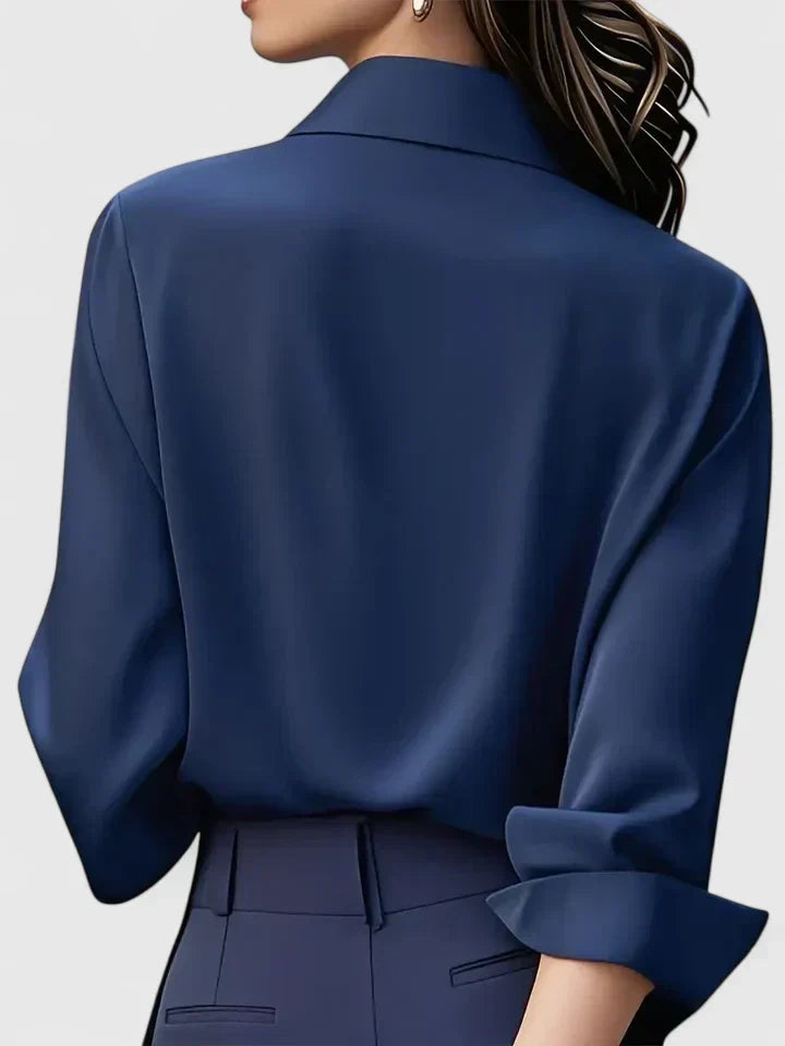 Back view of the navy blouse on a model, showing the smooth back, turned-up cuff and collar, worn with matching navy trousers. 6