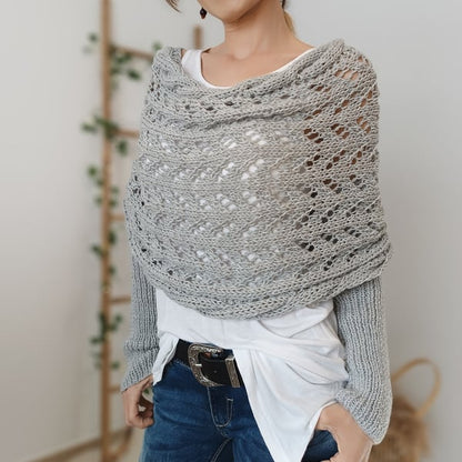 Close view of a light grey lace-knit wrap with ribbed sleeves, worn with a white top and belted jeans. 7
