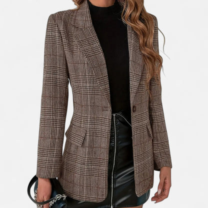 Close front view of the brown checked blazer worn open over a black top and black faux-leather skirt, showing lapels, flap pockets and one button. 1