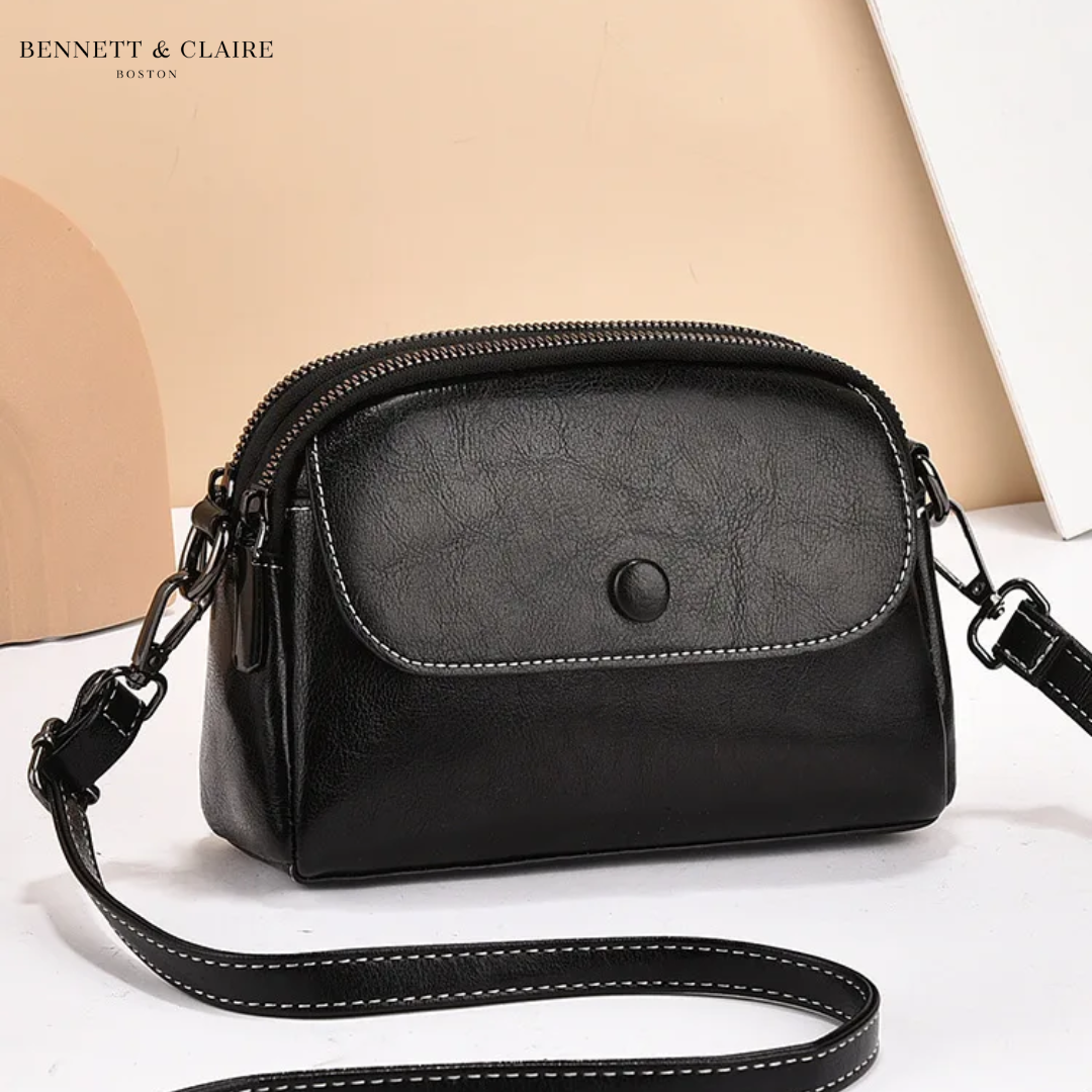 Black version of the crossbody bag, with contrast stitching on the front flap and strap, and dark metal clip hardware. 2