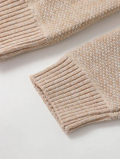 Close-up of the ribbed cuffs of the beige knit cardigan, with the textured knit of the sleeves above them. 6