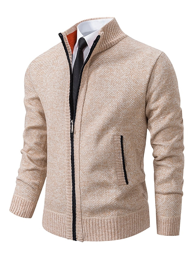 Beige knitted zip-up cardigan with stand collar, black zip trim and side pockets, shown front-on over a white shirt and black tie. 1