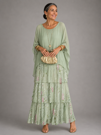 Woman in a pale mint green cape top over a tiered maxi skirt with a delicate pink and white floral print. 12